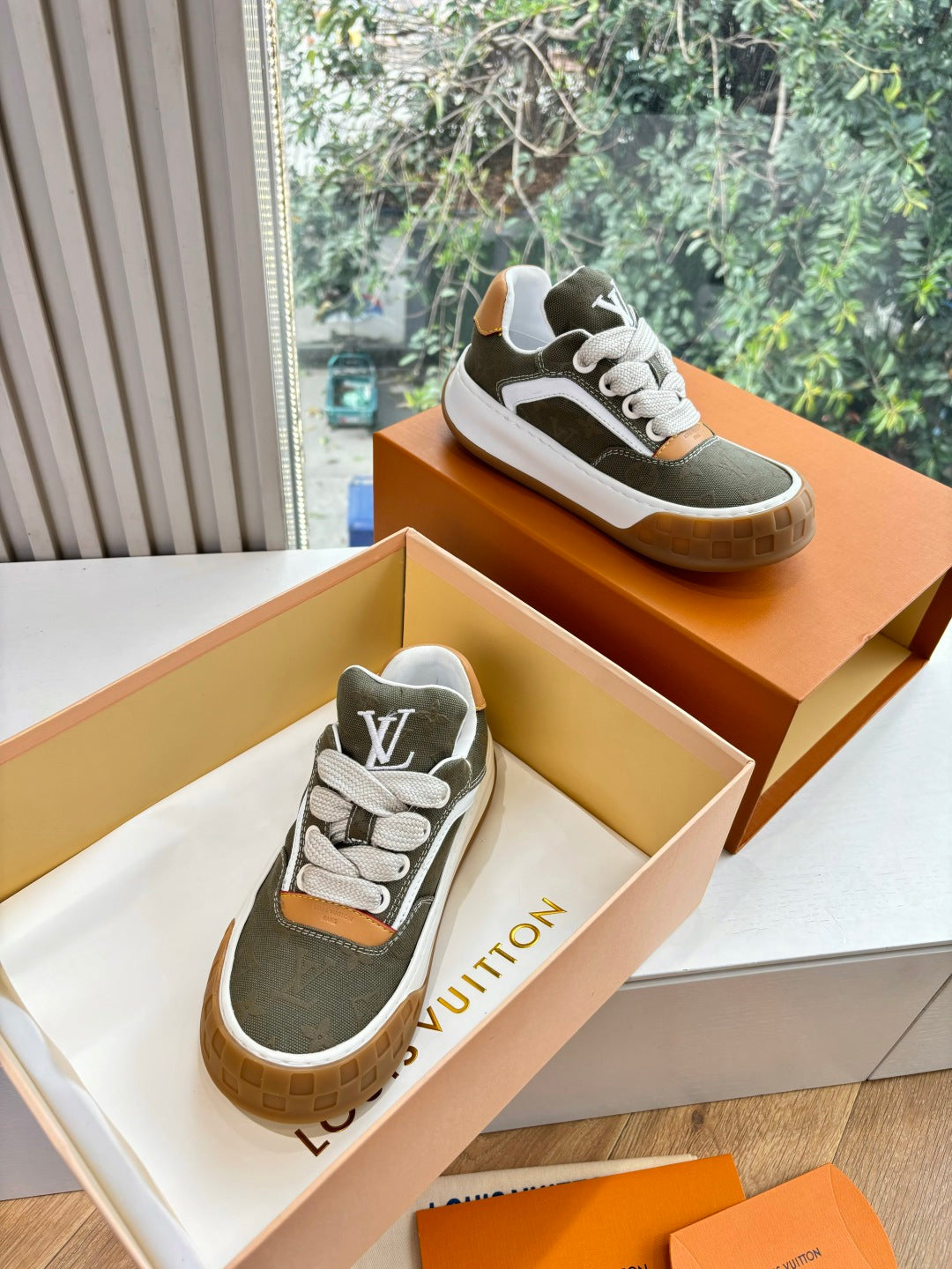 Unisex Louis Vuitton low-top sneakers, dark green fabric with white midsole and orange accents.
