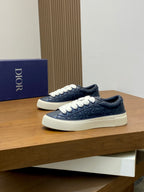 Navy low-top Dior sneakers with white laces on a wooden display shelf