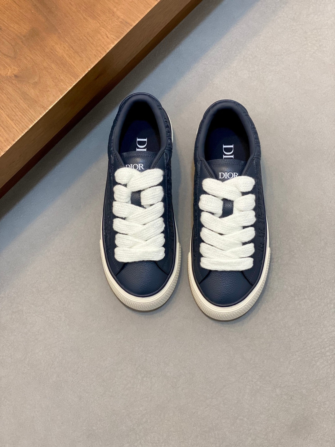 Navy low-top sneakers with white laces and Dior branding on the tongue