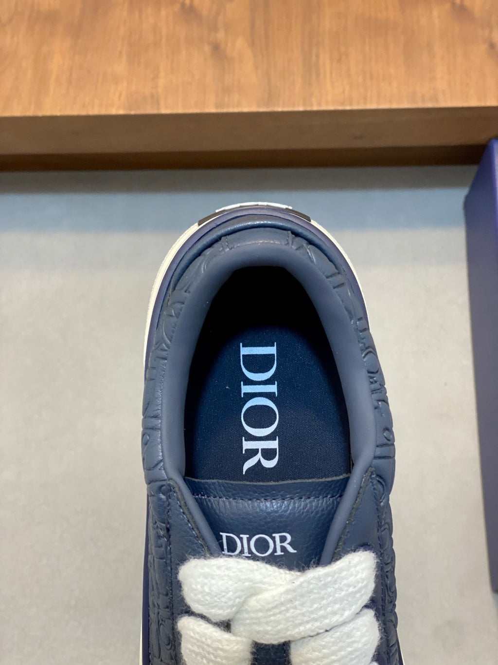 Close-up of navy sneaker tongue with Dior logo and white laces