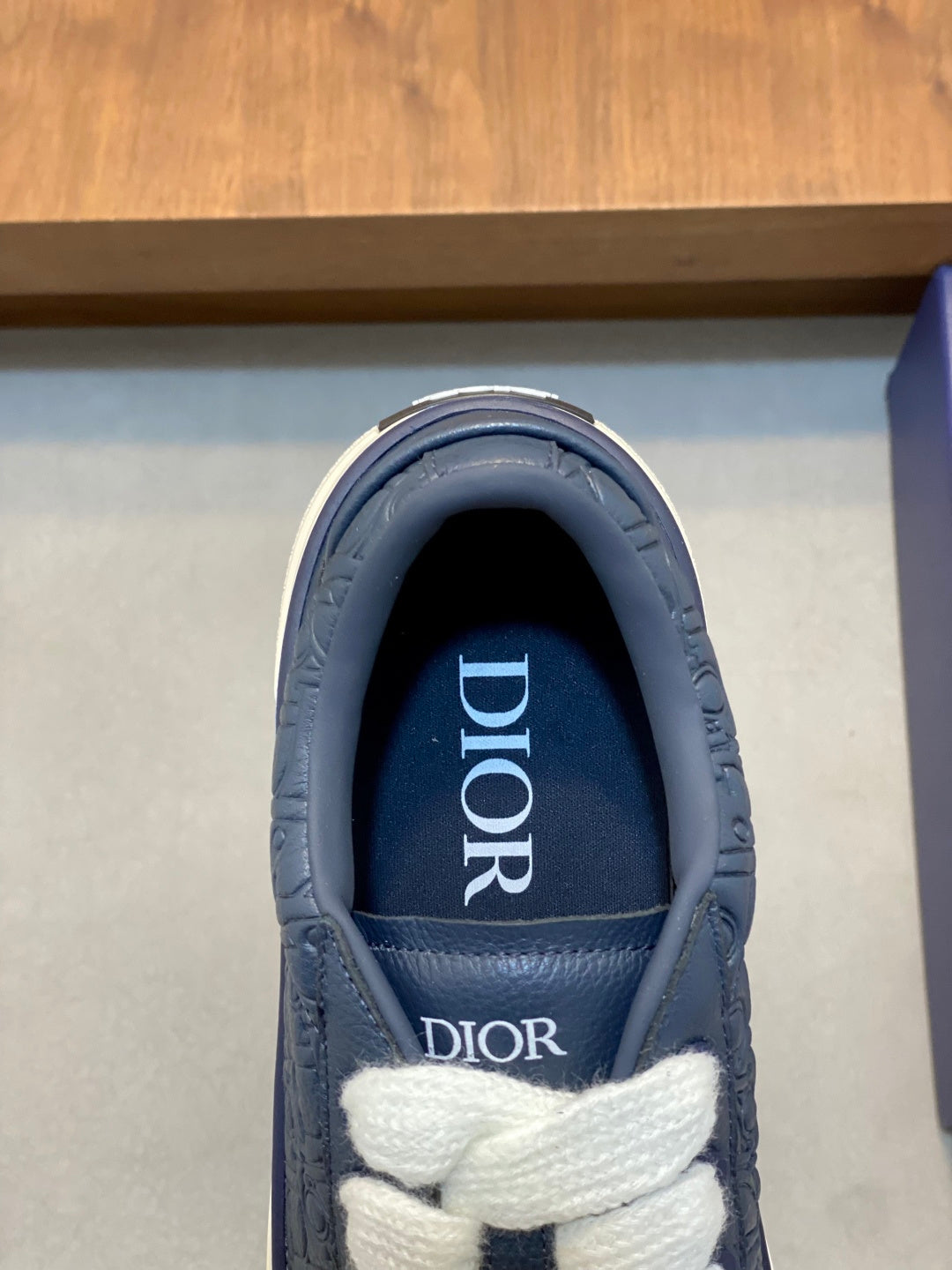 Close-up of navy sneaker tongue with Dior logo and white laces
