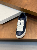 Navy low-top Dior sneaker with white laces displayed on a wooden shelf