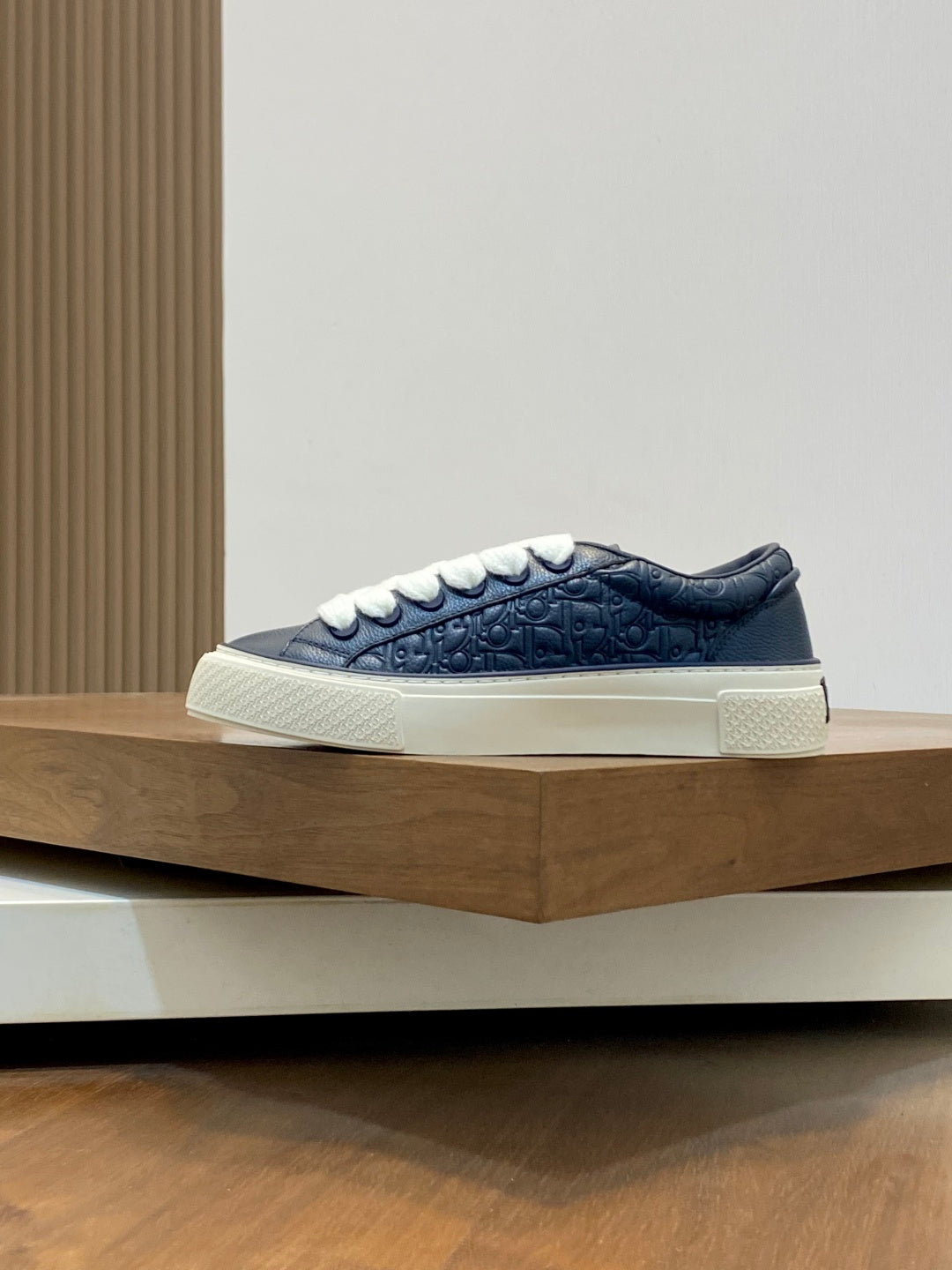 Navy low-top sneaker with white laces, embossed texture, and thick white sole