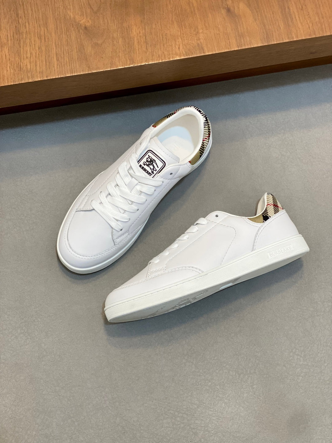 White low-top sneakers with lace-up front, signature logo tongue, and trim