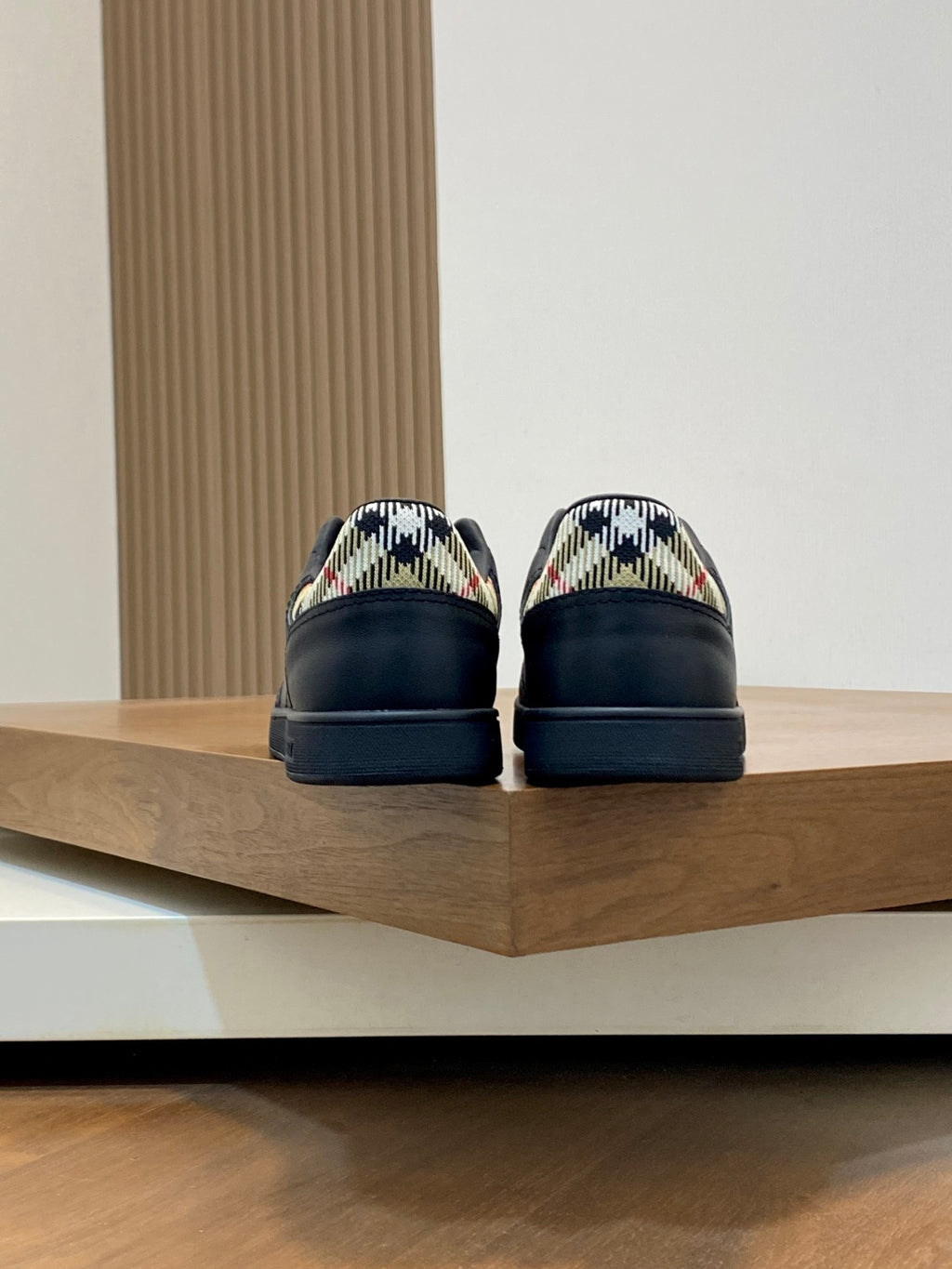 Black low-top sneakers with plaid heel lining and rear tabs