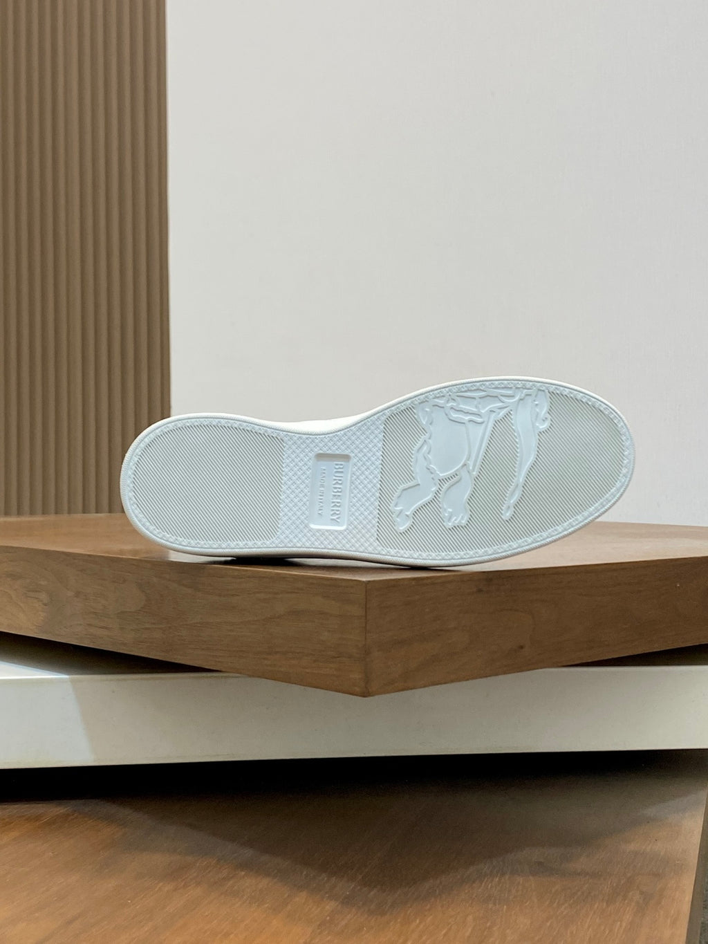 White sneaker outsole view with textured traction pattern and heel branding