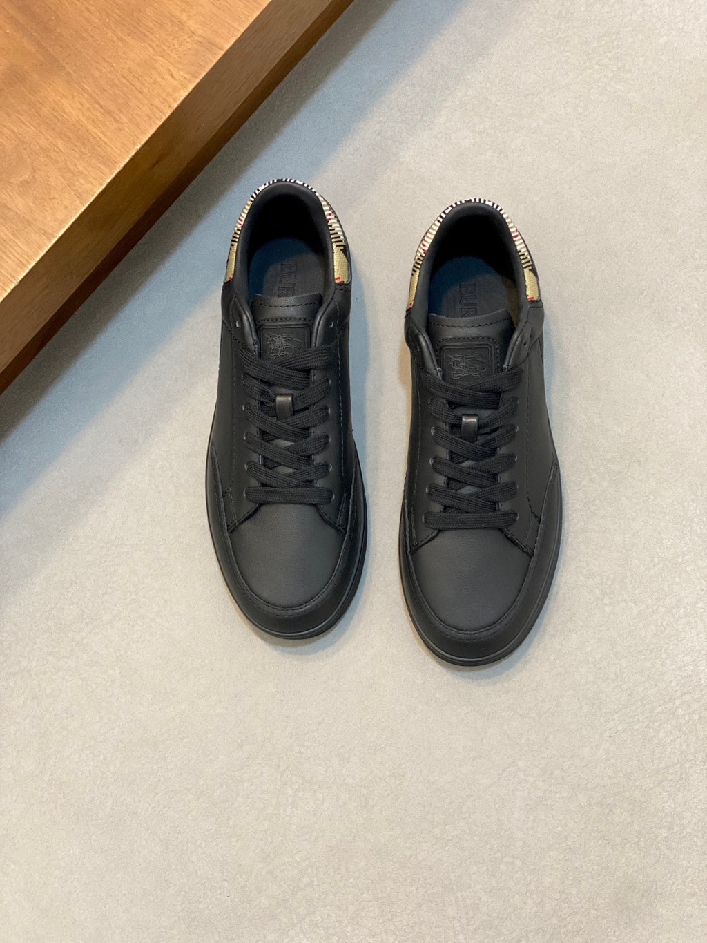 Black low-top lace-up sneakers with plaid heel detail
