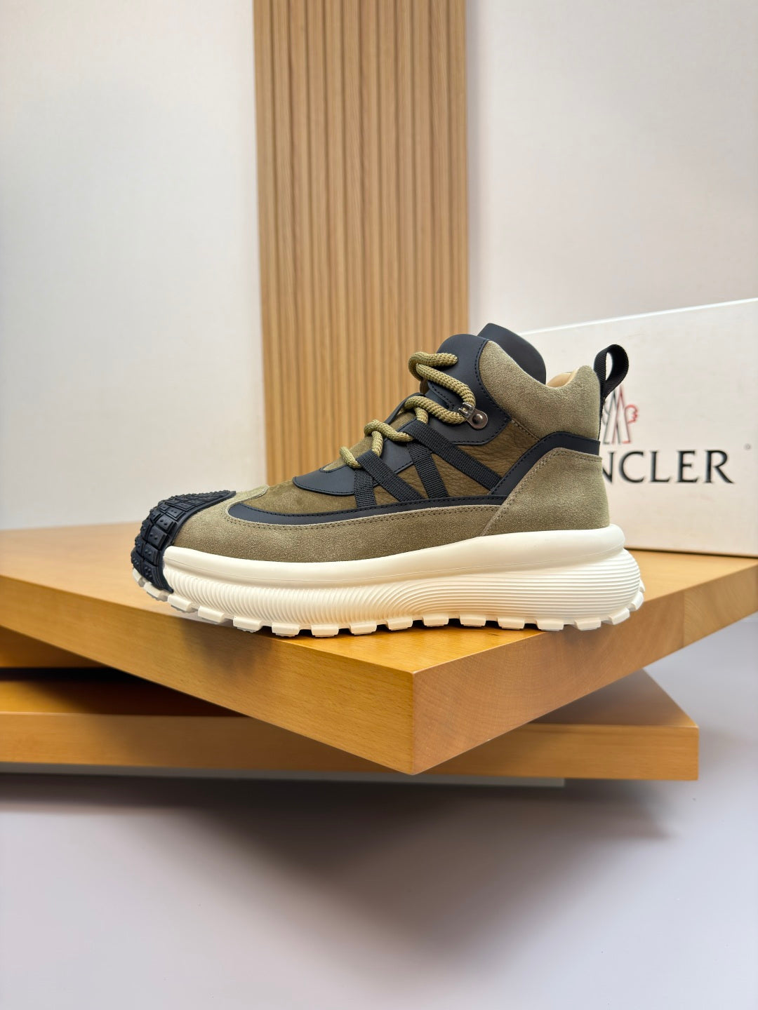 Moncler sneakers on display: olive and black upper with neon-yellow laces and white sole