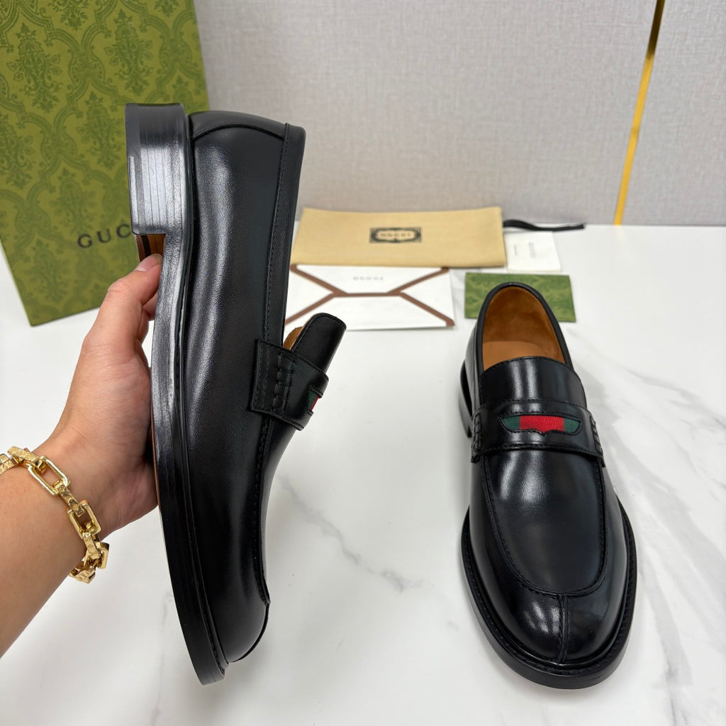 Gucci black leather loafer, hand-held side profile, slip-on with red green detail