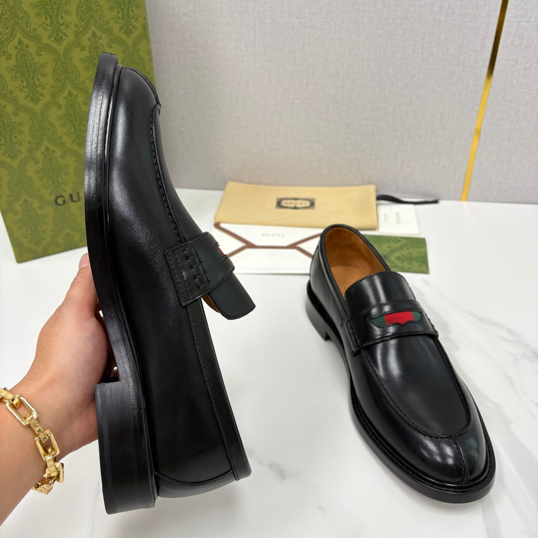 Gucci black leather loafers, angled side view, slip-on with red green stripe