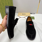 Gucci unisex black suede loafers shown on hand, side buckle detail and stripe.
