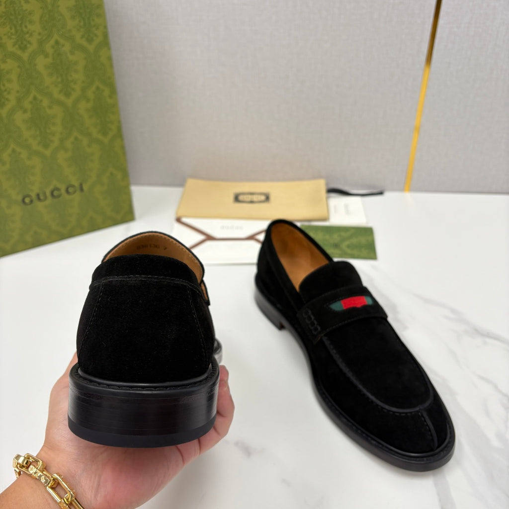 Gucci unisex black suede loafers with stacked heel, held by hand, stripe on top.
