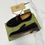 Gucci unisex black suede loafers, side view, with multicolor stripe detail.