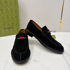 Gucci unisex black suede loafers, angled view, with multicolor stripe at vamp.