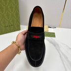 Gucci unisex black suede loafer close-up with multicolor stripe on front panel.