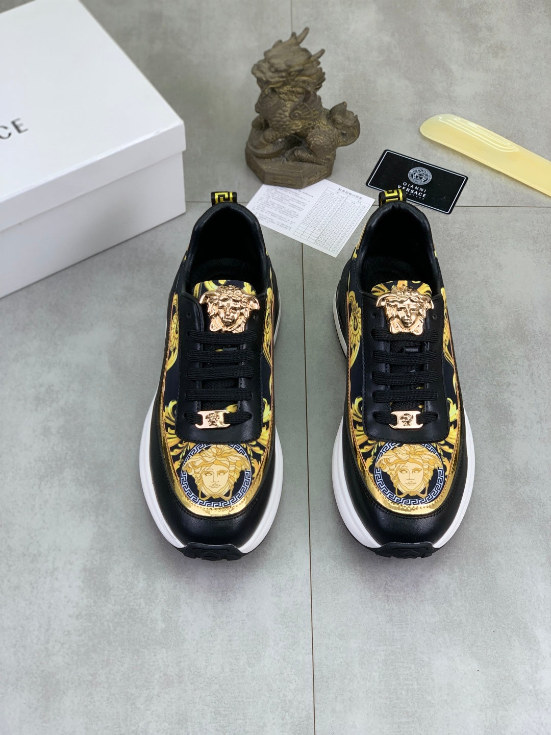Pair of Versace low-top sneakers in black with gold Medusa-style emblem and ornate accents