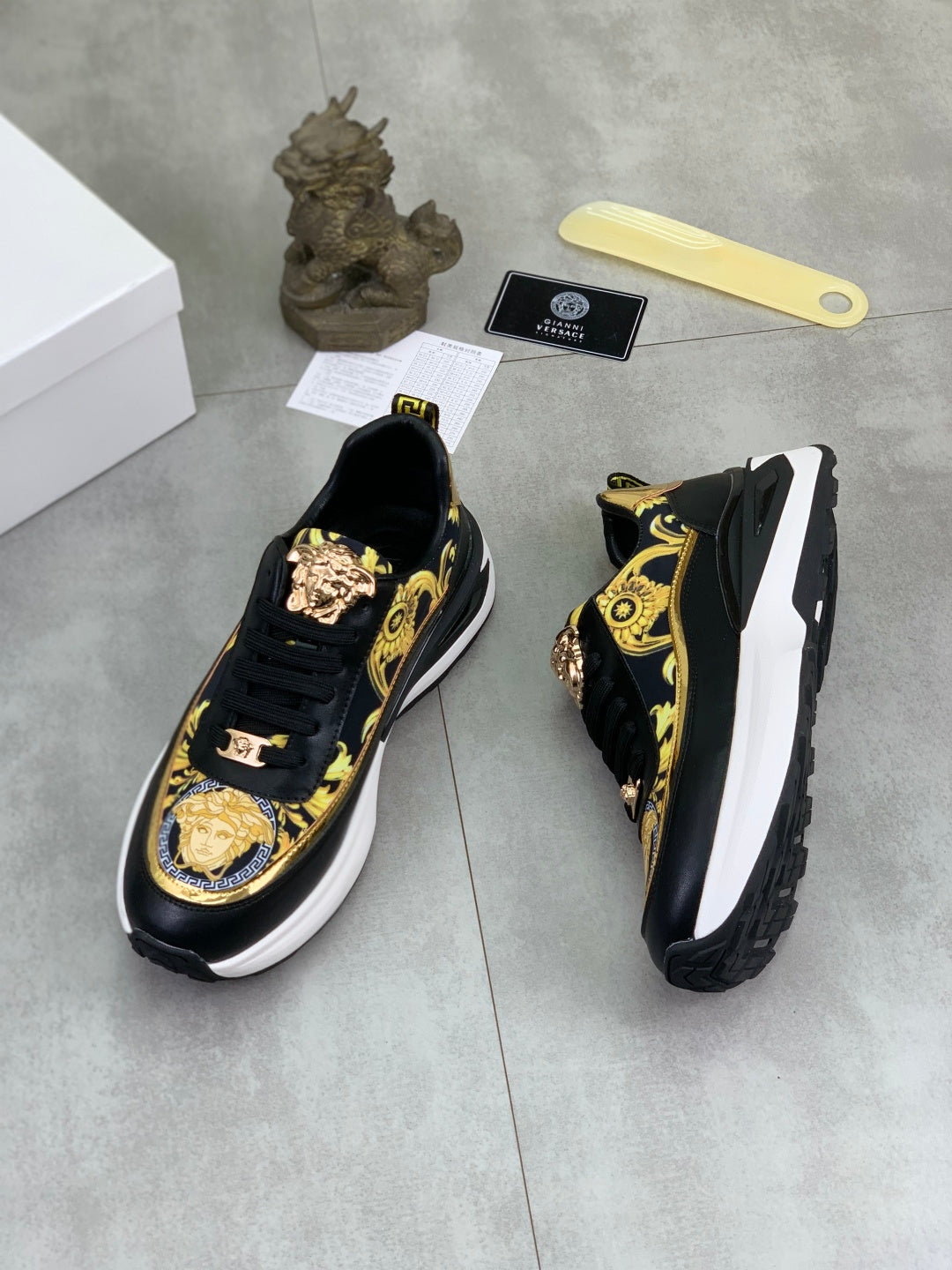 Versace low-top sneakers in black with gold ornate print and chunky white platform sole