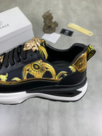 Versace low-top sneaker close-up: black and gold patterned upper with sculpted emblem on side
