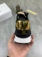 Versace low-top sneaker heel view, black upper with gold logo panel and white midsole