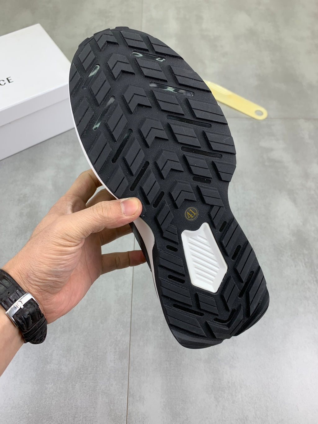 Versace sneaker outsole view, black rubber tread with white traction patch