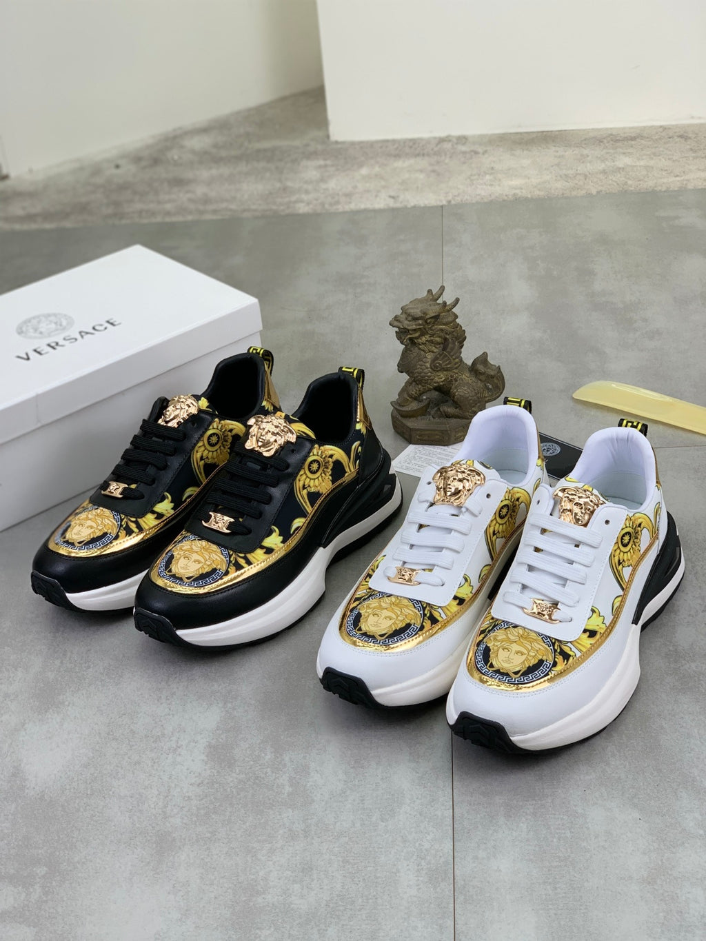 Versace sneaker pair: black-and-gold design and white-and-gold design with Versace crest