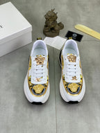Versace white low-top sneakers with gold emblem detailing and black-and-white rubber sole