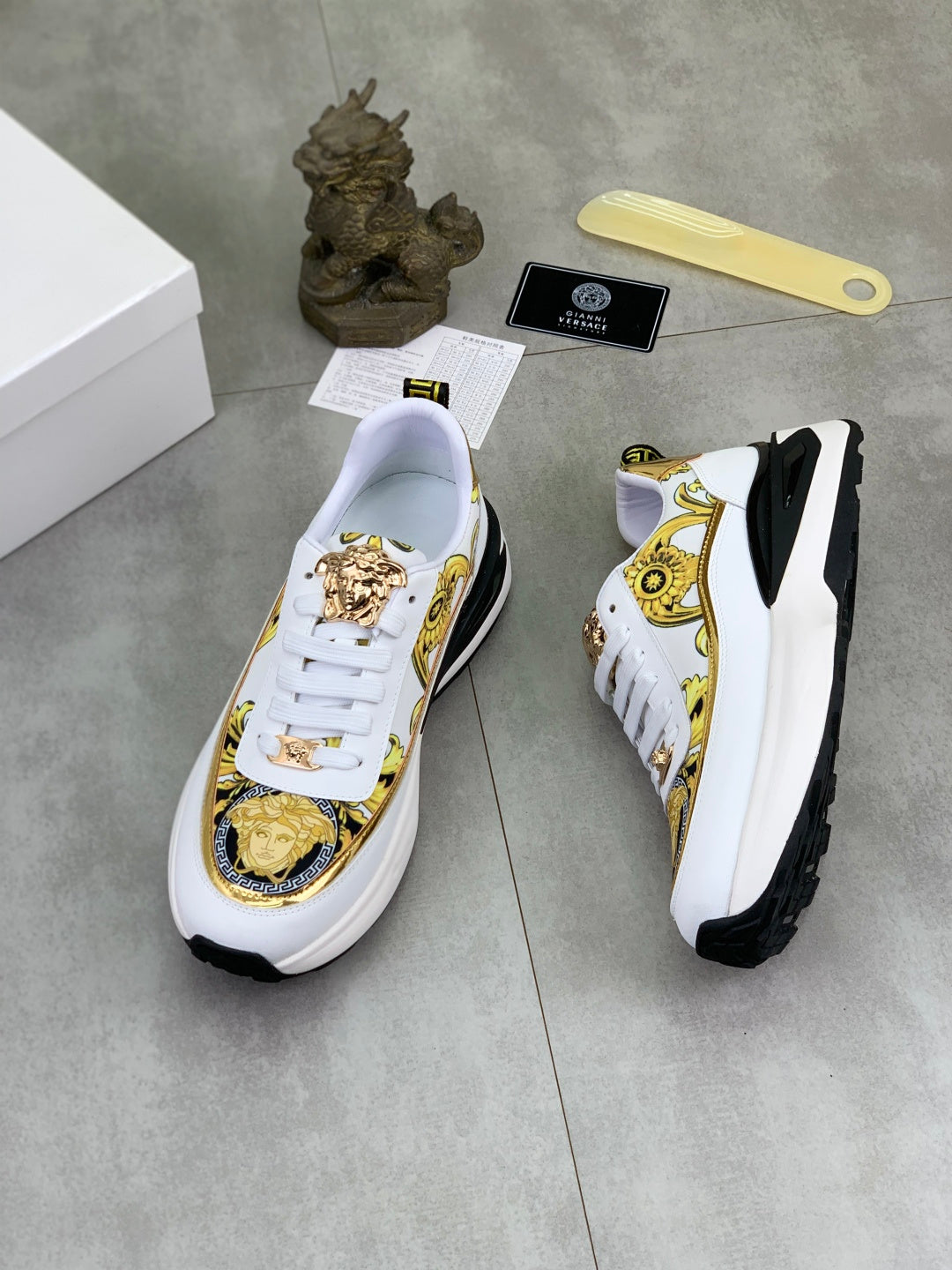 Versace white sneakers with gold crest accents, white laces, and thick black sole