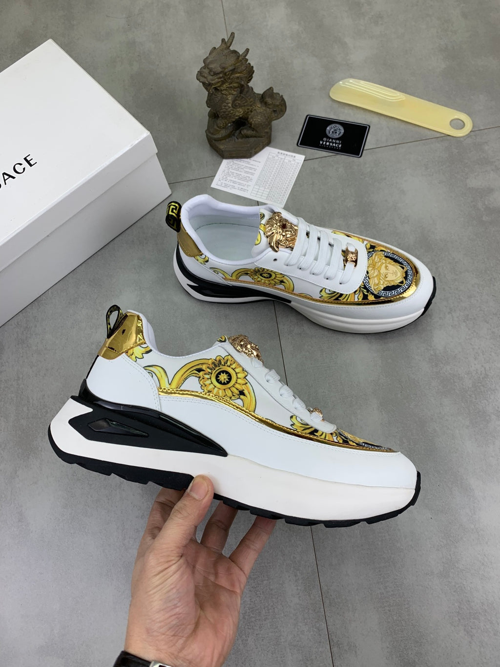 Versace white sneakers with gold-and-black pattern trim and thick athletic sole