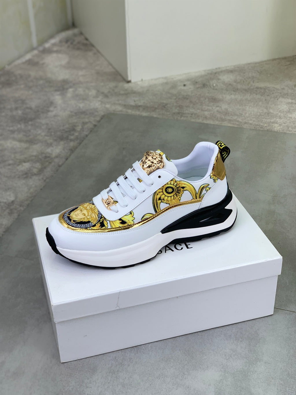 Versace white sneakers with gold ornate panel and chunky black-and-white platform sole