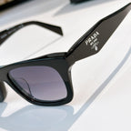 Close-up of black sunglasses frame and purple lens; Prada text on temple