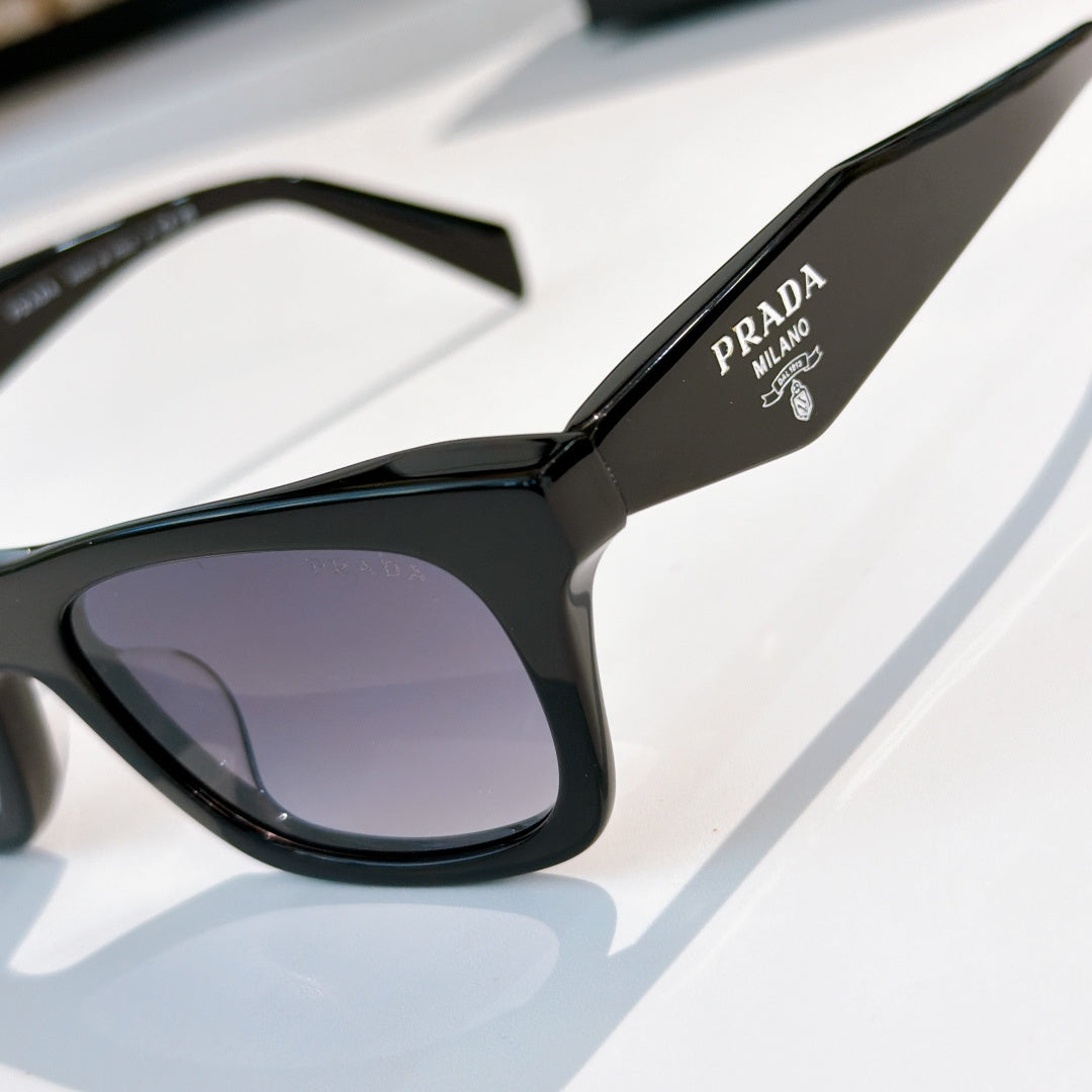 Close-up of black sunglasses frame and purple lens; Prada text on temple