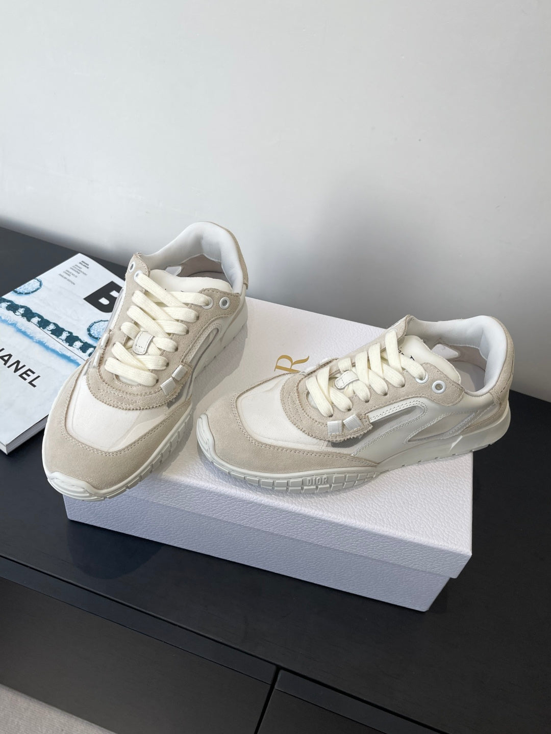 Cream lace-up sneakers with side panel logo detail and textured outsole, pair on box
