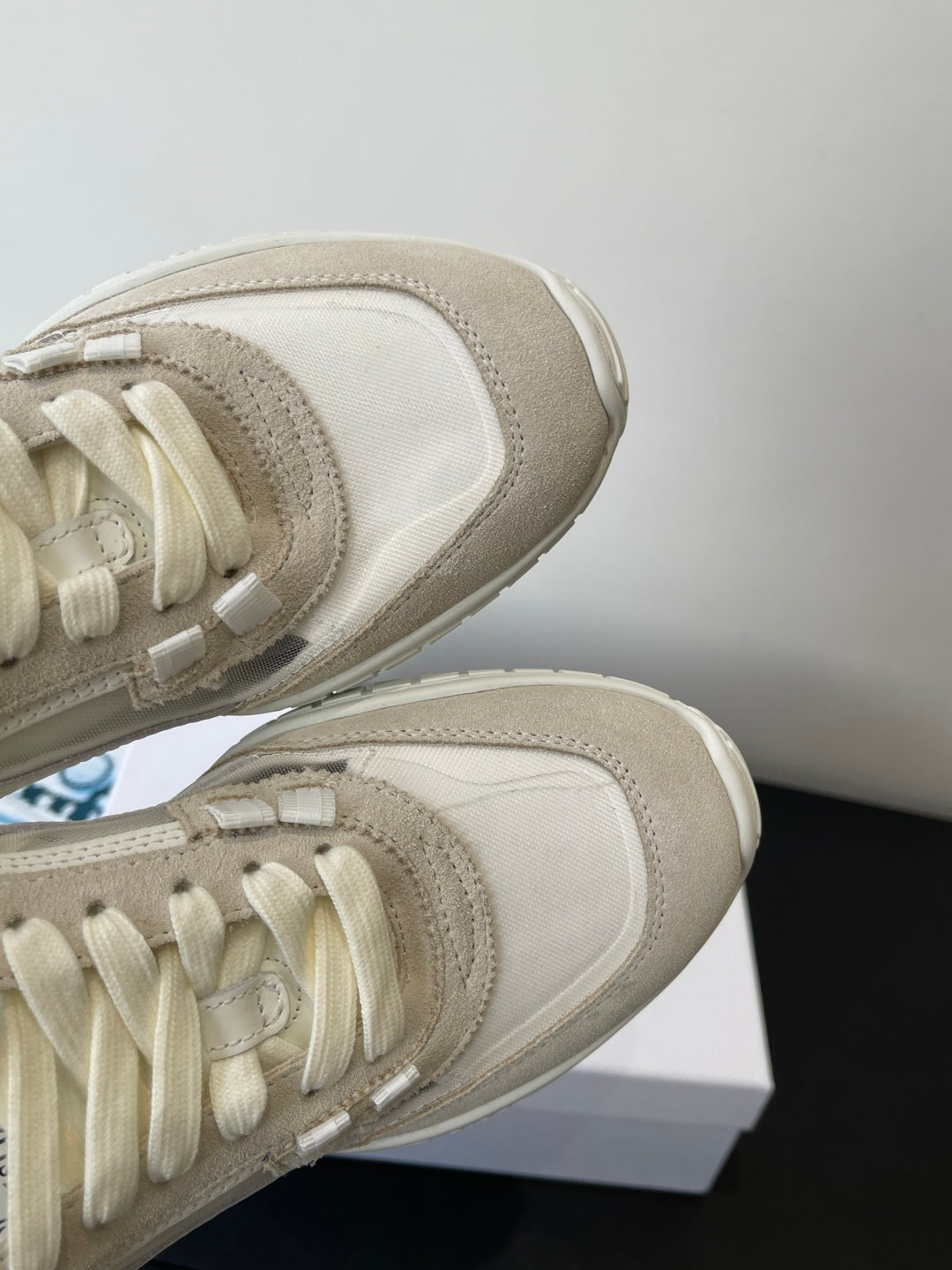 Cream lace-up sneakers with suede and fabric overlays, close-up of laces and toe