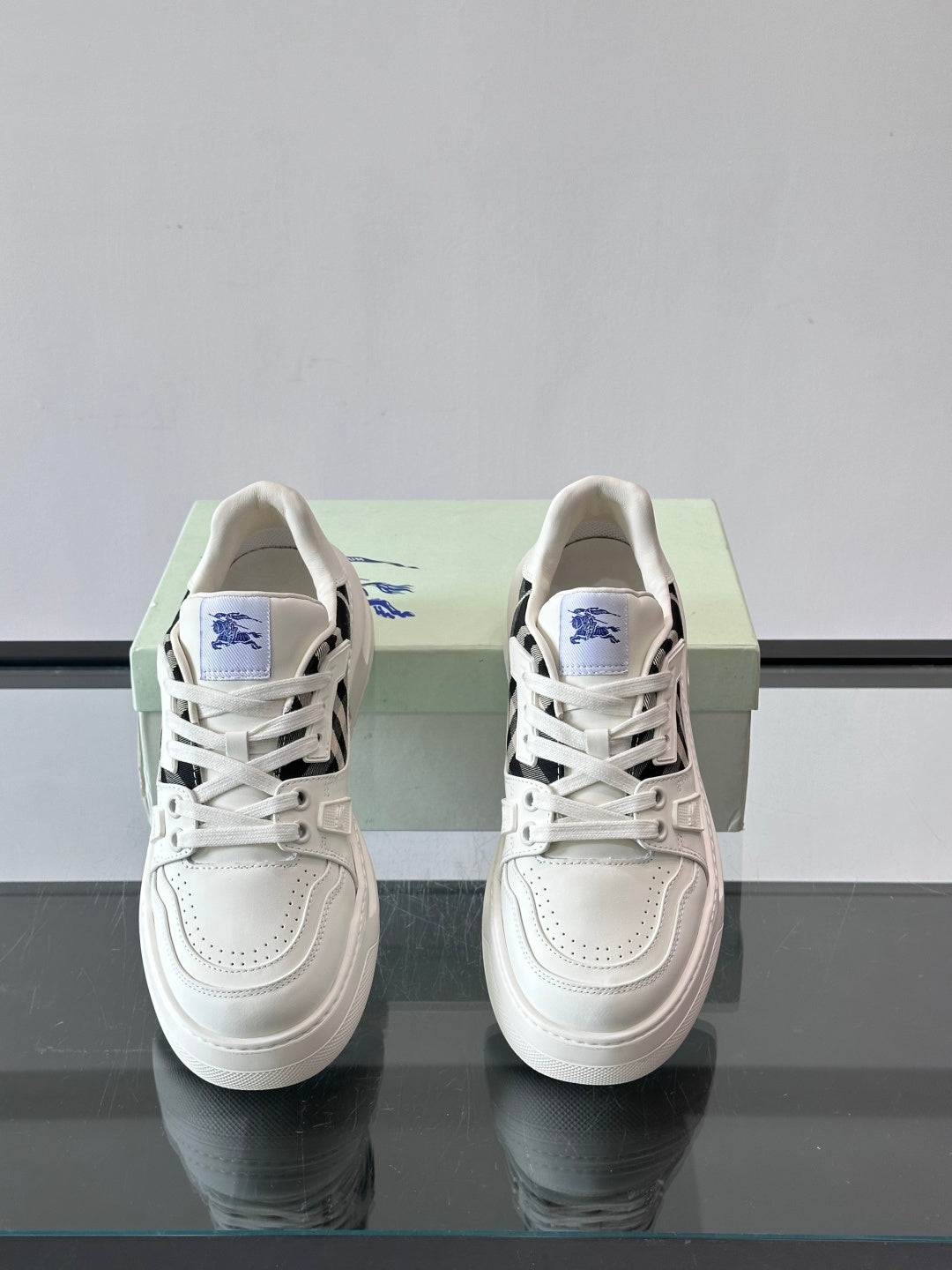 Front lace-up sneakers with white uppers, black check panel, blue logo patch