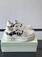 White lace-up sneakers with black check panel and blue logo, chunky rubber sole