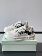 White lace-up sneakers with black plaid side insert and blue emblem on tongue