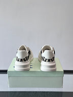 White lace-up sneakers back view with heel tab and blue logo patch