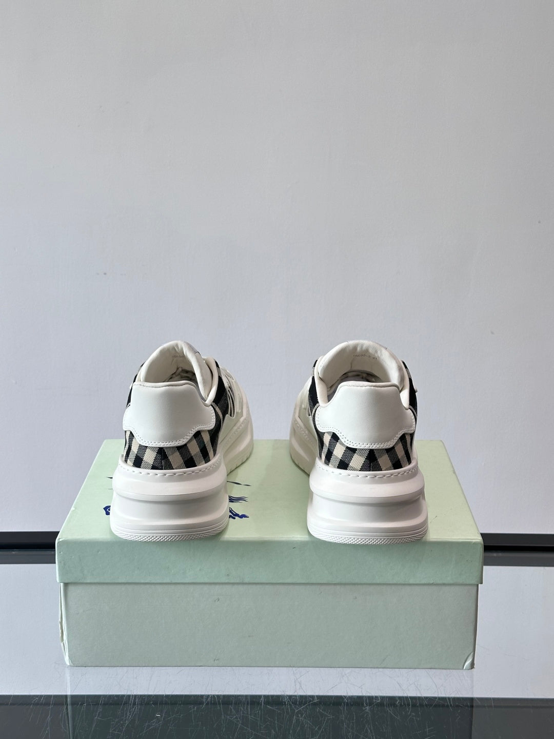 White lace-up sneakers back view with heel tab and blue logo patch