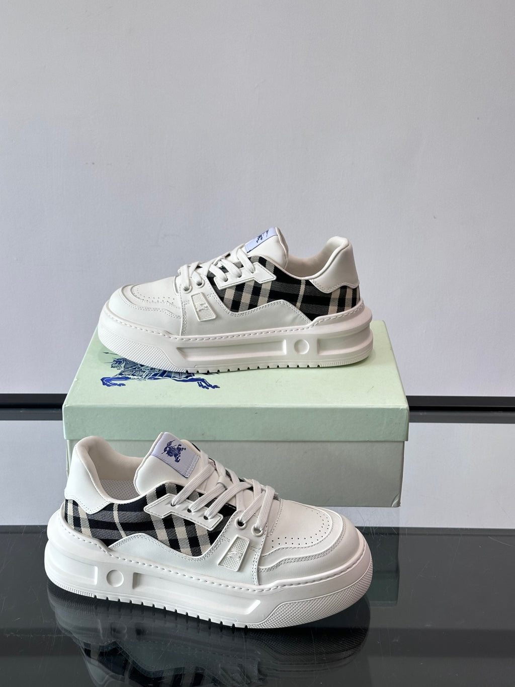 White lace-up sneakers with black check panel, blue wing emblem, thick sole
