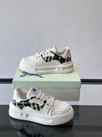 White lace-up sneakers with black check panel, blue wing emblem, thick sole