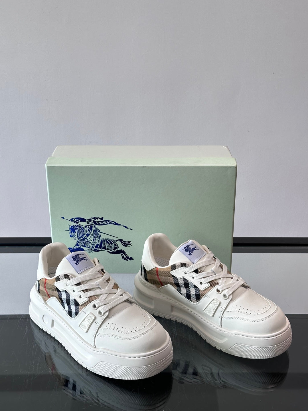 White sneakers with blue horse logo on side and black-and-brown check panel