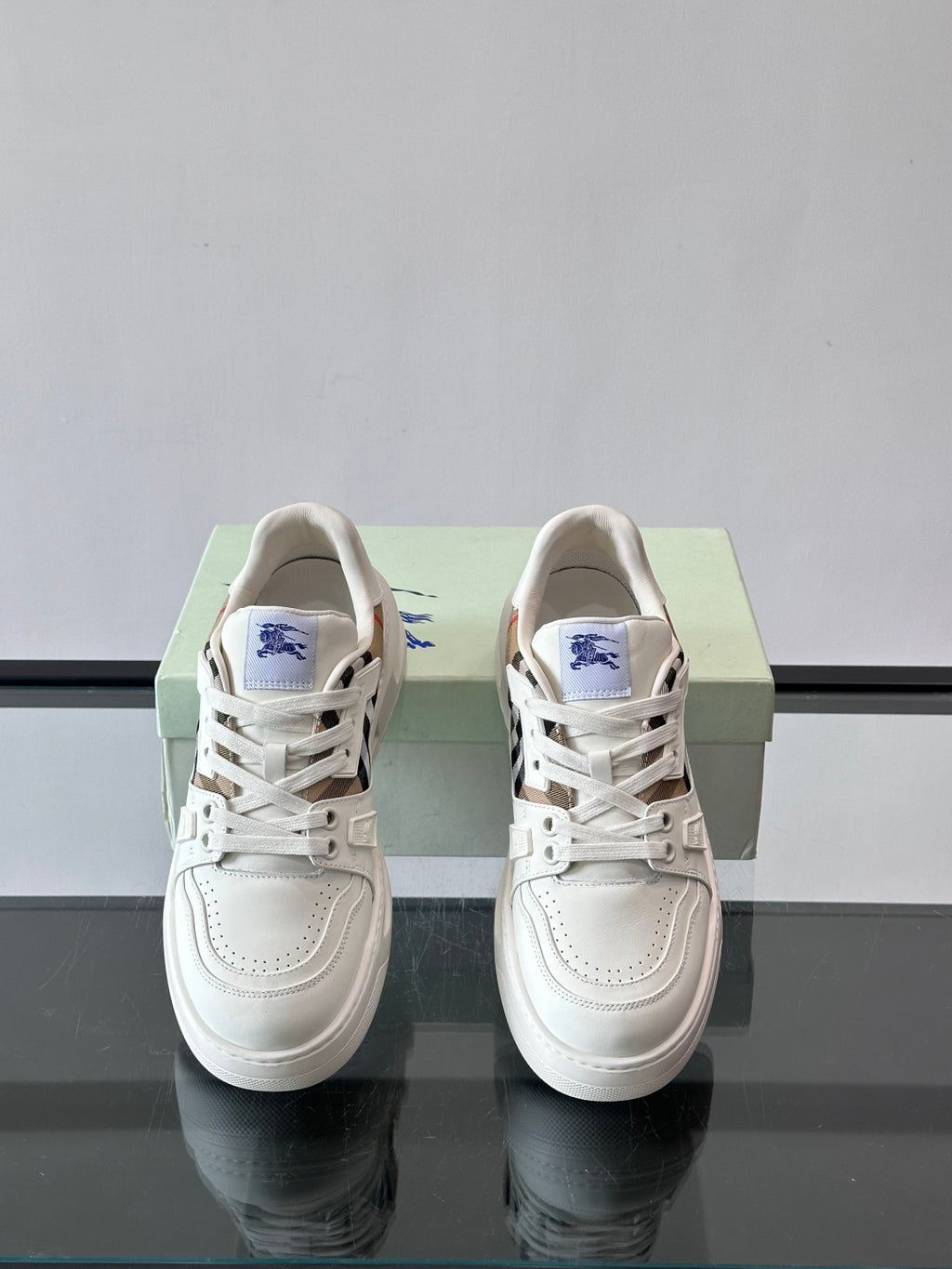White lace-up sneakers with blue emblem on tongue and check-pattern side trim