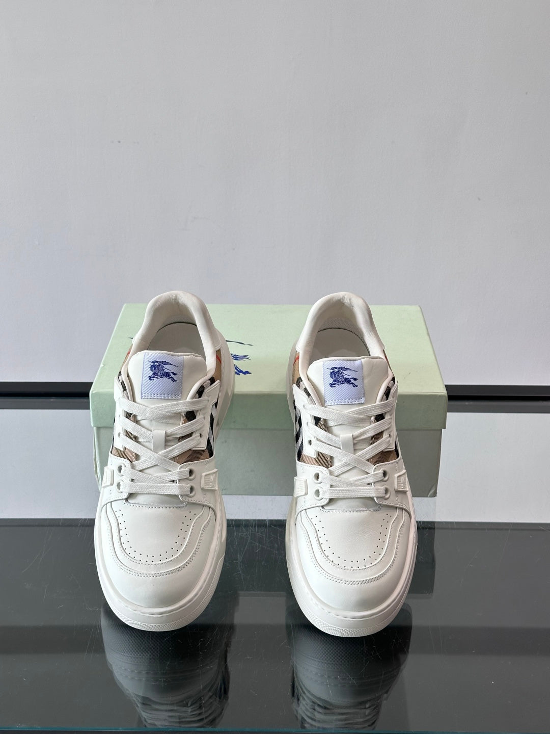 White lace-up sneakers with blue emblem on tongue and check-pattern side trim