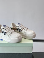 Two white sneakers on box with black-and-brown plaid side panel and blue logo