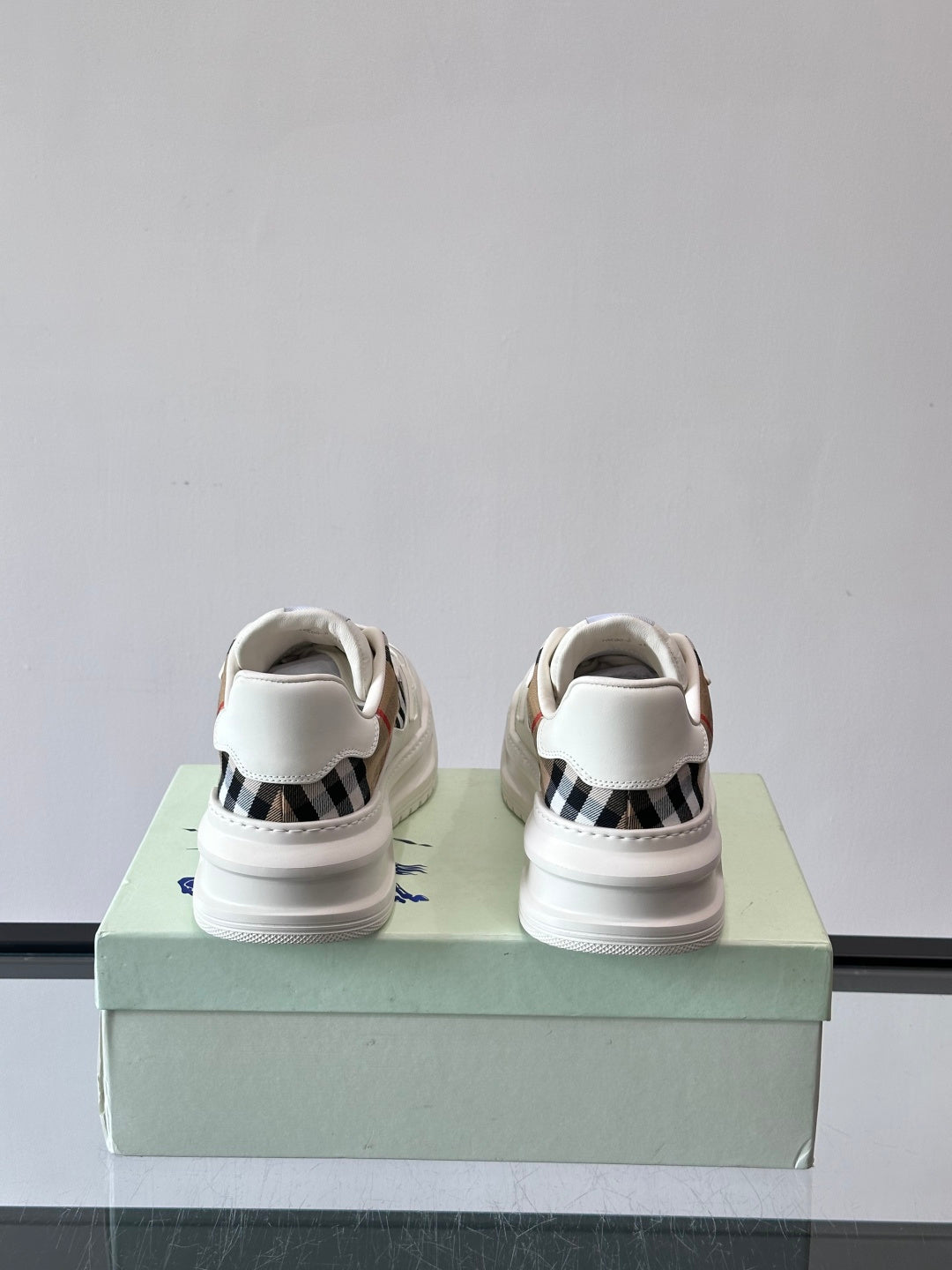 White sneakers viewed from back with blue heel logo and low-profile sole