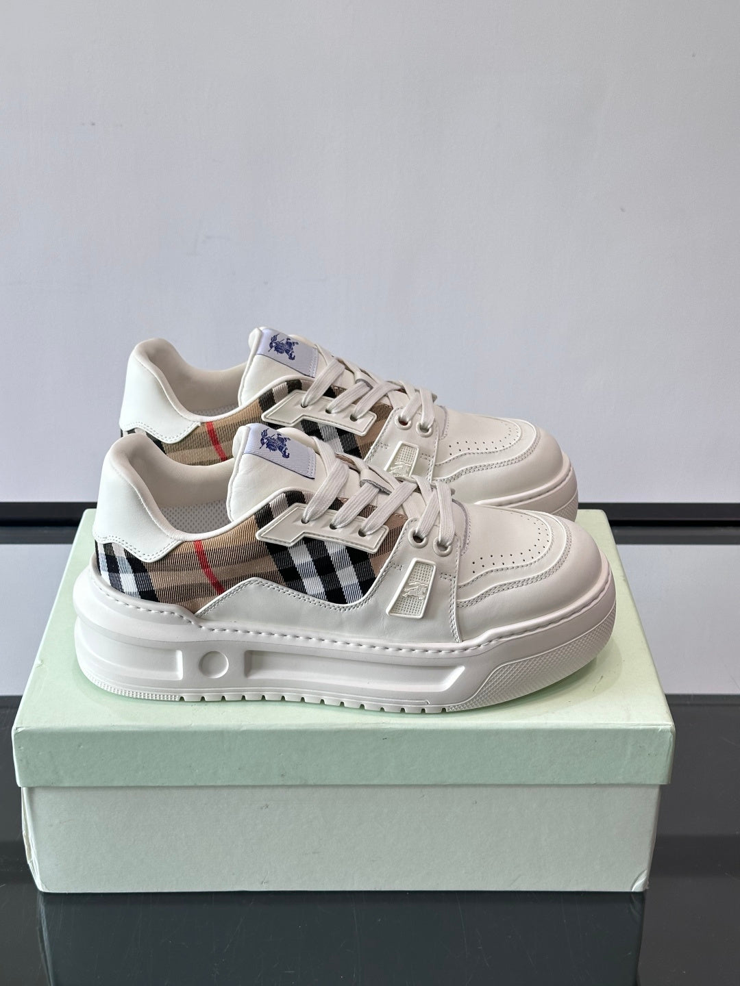 White leather lace-up sneakers with plaid side panel and blue logo on tongue