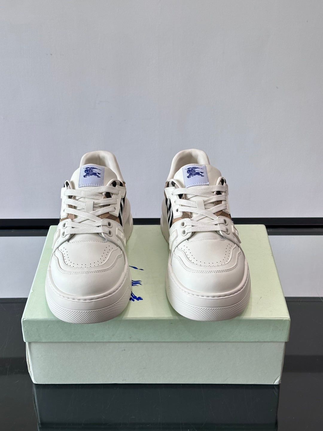 Pair of white lace-up sneakers with blue emblem and check-pattern side accents