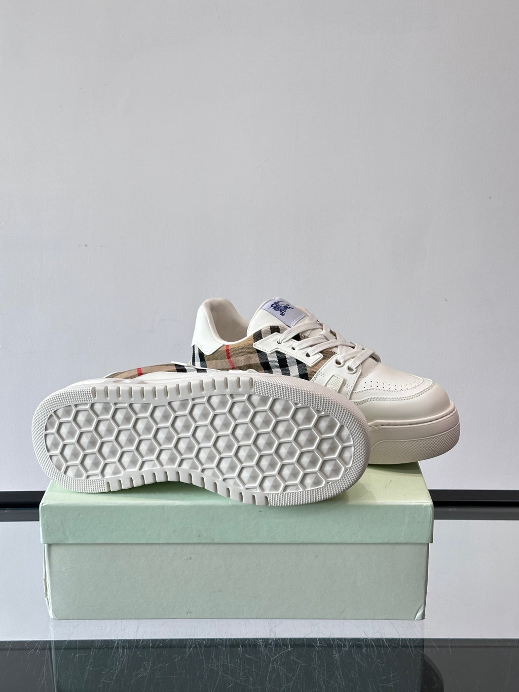 White sneaker outsole with hex tread pattern, shown from side on box
