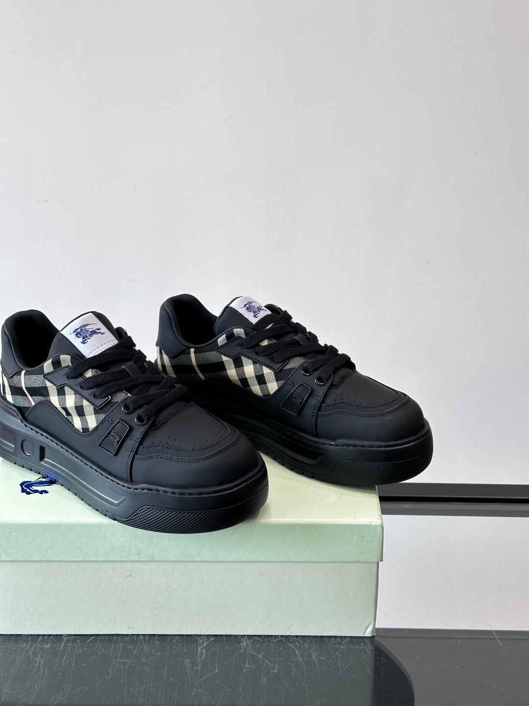 Black lace-up sneakers with check panel detail shown side by side