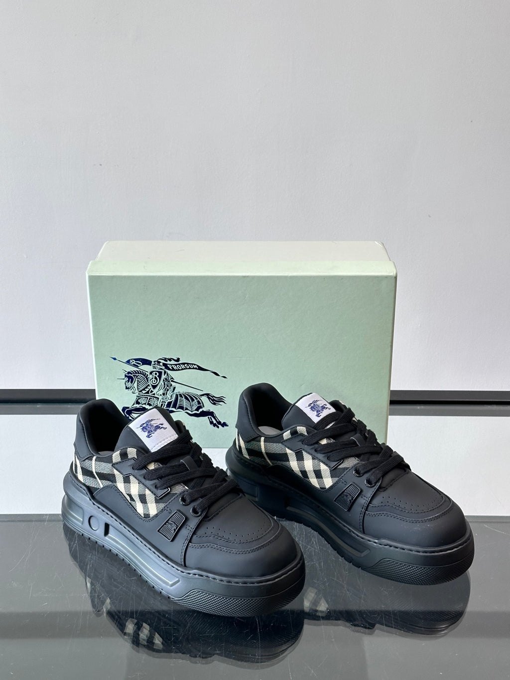 Two black lace-up sneakers with check panel accents on the sides
